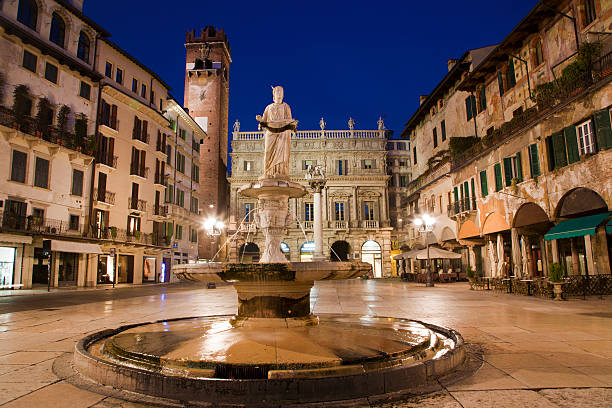 Verona - Fountain on Piazza Erbe in dusk and Porta Leona and Palazzo Maffei in backgroud