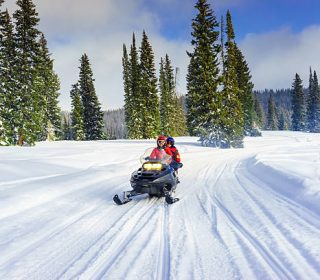 mother and son driving a snowmobile in  colorado, usa
