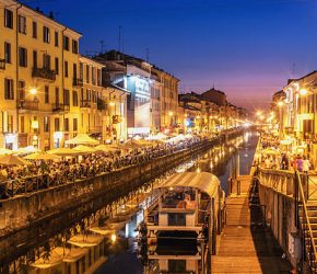 People dining and promenading along the busy canal "Naviglio Grande" on a Saturday evening.