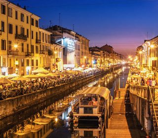 People dining and promenading along the busy canal "Naviglio Grande" on a Saturday evening.